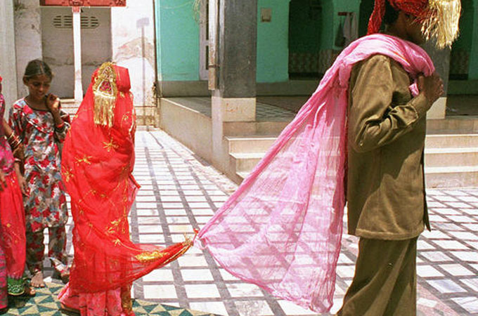 Eight year old bride follows new husband to visit temple after marriage ceremony, with his family, Rajasthan, India