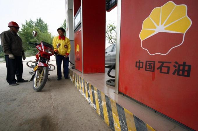 File picture shows a station attendant filling a motorcycle''s petrol tank at a PetroChina gas station in Suining, Sichuan province