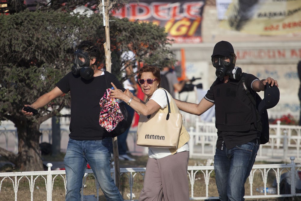 <p>Plain clothes policemen help a tourist to get away from tear gas as Turkish police raid Taksim Square this morning. Since the protests began, a once healthy tourism industry is now at a standstill.</p>