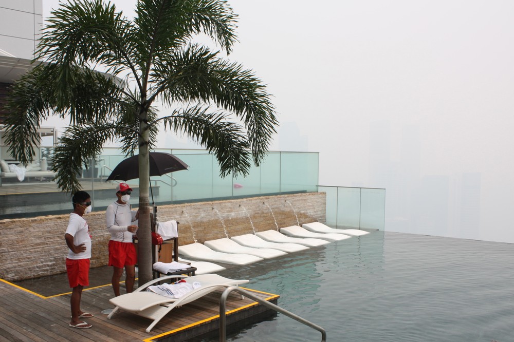 <p>Two lifeguards wear masks at a swimming pool on the top floor of the Marina Bay Sands Hotel as haze hits Singapore. </p>
