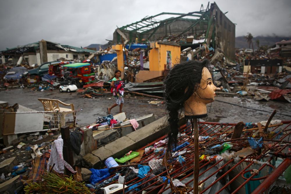 A Typhoon Haiyan survivor carrying her clothes looks at a mannequin(***)s head which was put on a stick as she walks through the ruins of Tacloban City, on November 22, 2013.