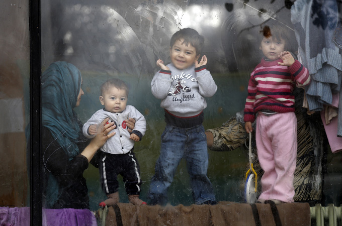 Syrian refugee children look through a window inside a Bulgarian Red Cross refugee centre [Reuters]