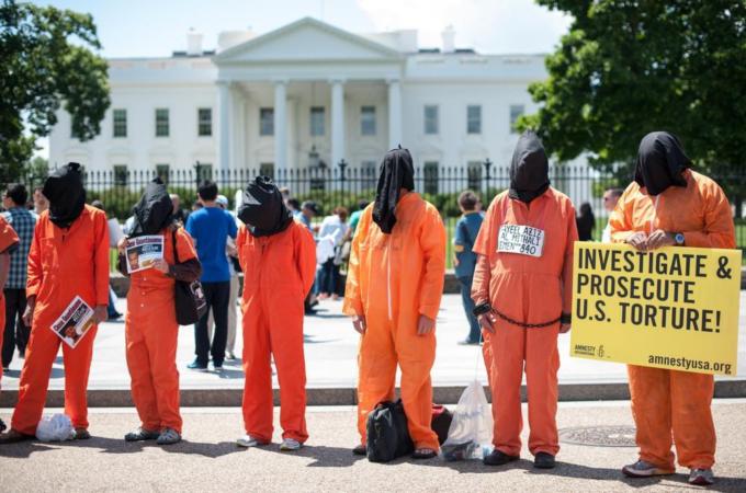 Protesters hold signs as they call for the closing of the Guantanamo Bay detention facility in front of the White House in Washington DC [AFP]