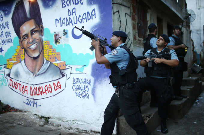 Pacification Unit officers patrol next to a mural of slain dancer Douglas Rafael da Silva Pereira [Getty Images]