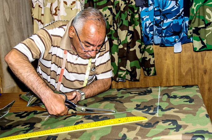 Tailor Abu Mohammad said he makes more than 35 military uniforms each day [Ridha Al Shammry/Al Jazeera]