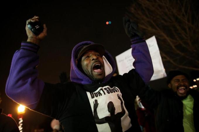 Demonstrators chant 'hands up, don't shoot' as they protest in front of the Ferguson police department [Getty]