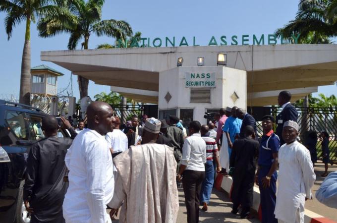 Nigerian parliament members gather at the national assembly gate closed by security forces in Abuja on November 20, 2014. [AFP]