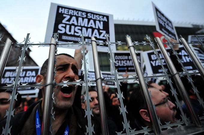 Staff members and supporters of Zaman newspaper shout slogans and hold placards reading 'Free press can not be silenced' during a protest against a raid by counter-terror police in Istanbul [AFP/Getty Images]