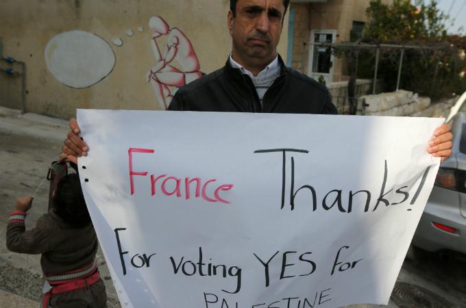 A Palestinian man holds a poster as he calls on France to vote for the recognition of a Palestinian state [AFP]
