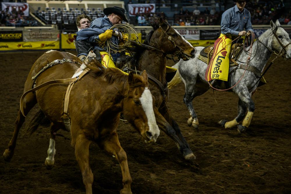 A competitor jumps off his bucking horse and clings onto an official during the bronco-riding event at the Oklahoma State Fair grounds in Oklahoma City.