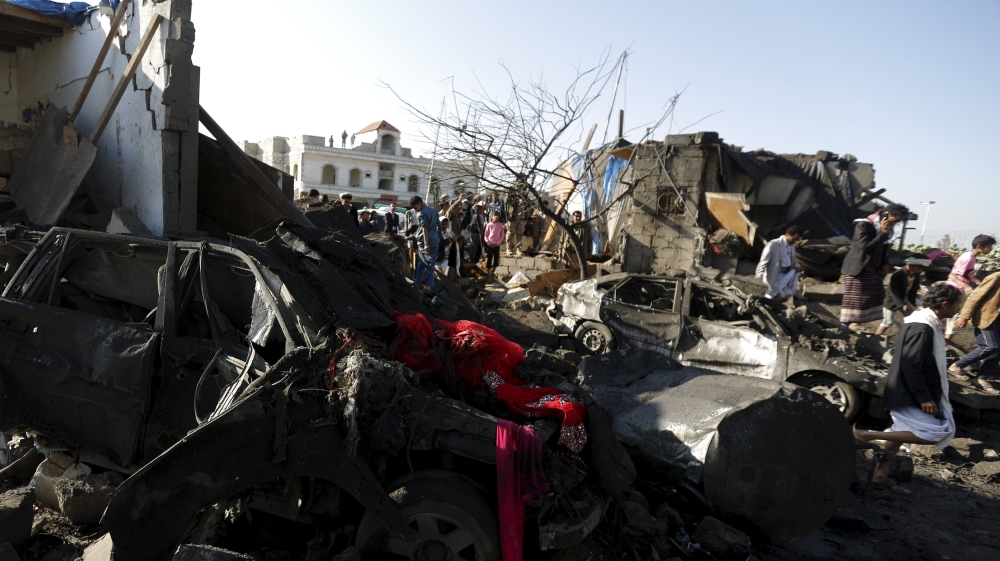 People gather at the site of an air strike at a residential area near Sanaa Airport