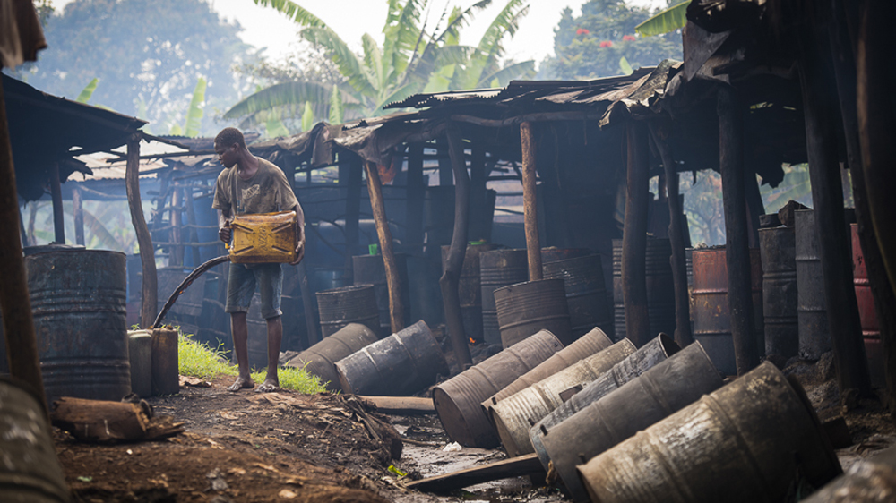 The black sticky residue from the distilling process flows through the open drains of Kimasa [AJ Heath/Al Jazeera]