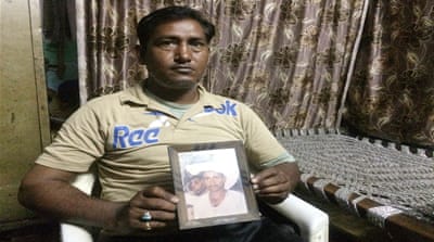 Mohammed Qadir holds up a photo of his father whose body was never found  [Sonia Paul/Al Jazeera] 