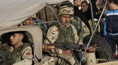 Egyptian military police stand guard where the bodies of soldiers who died in attacks in north Sinai were being turned over to relatives [AP]