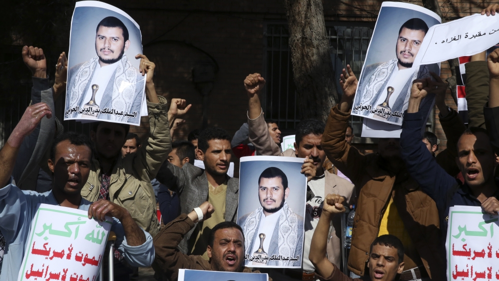 Yemeni men chant slogans while holding posters of Houthi rebel leader [AP]