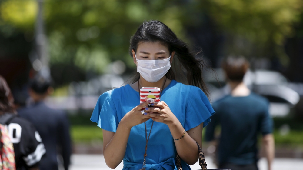 A woman wearing masks to prevent contracting Middle East Respiratory Syndrome (MERS) uses her mobile phone at Myeongdong shopping district in central Seoul