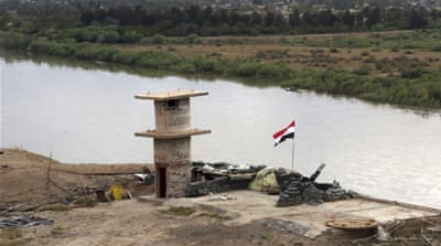 An Iraqi flag waves over the Tigris River at a checkpoint in Tikrit [AP]