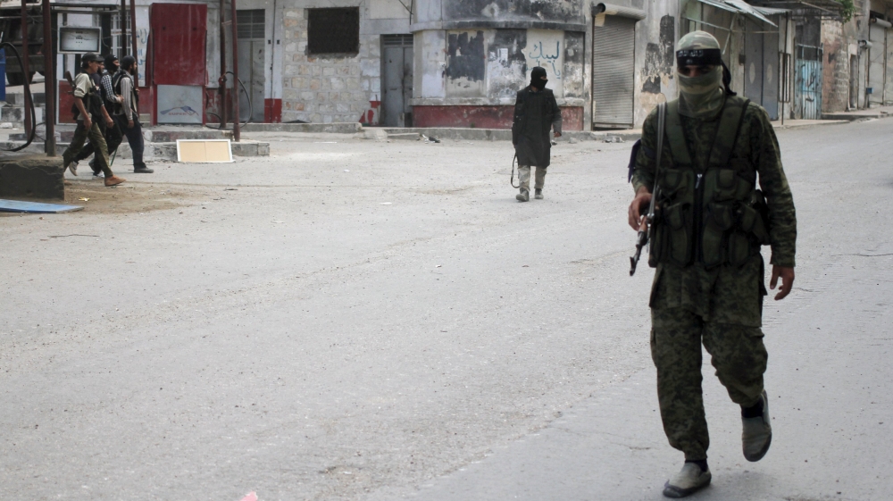 Members of Nusra Front walk along a street in the northwestern city of Ariha in Idlib province [REUTERS]