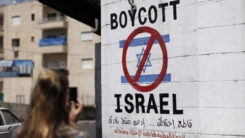 A sign painted on a wall in the occupied West Bank town of Bethlehem calling for a ban on Israeli products made in Palestinian occupied territories [Thomas Coex/AFP]