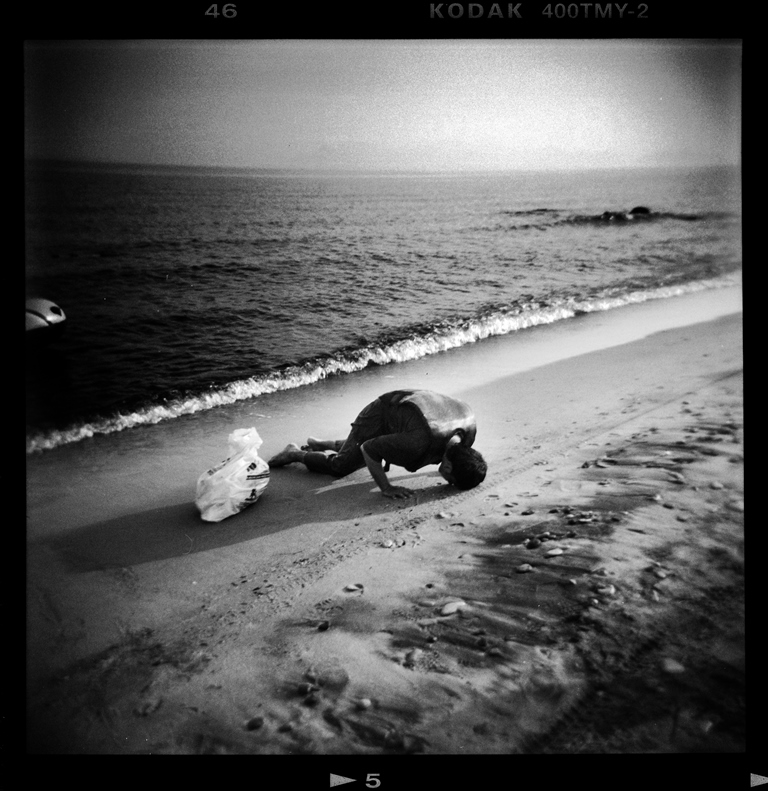 A refugee prays after arriving on a dinghy on Lambi beach on the Greek island of Kos - Kos, Greece, August 2015 [Giorgos Moutafis]