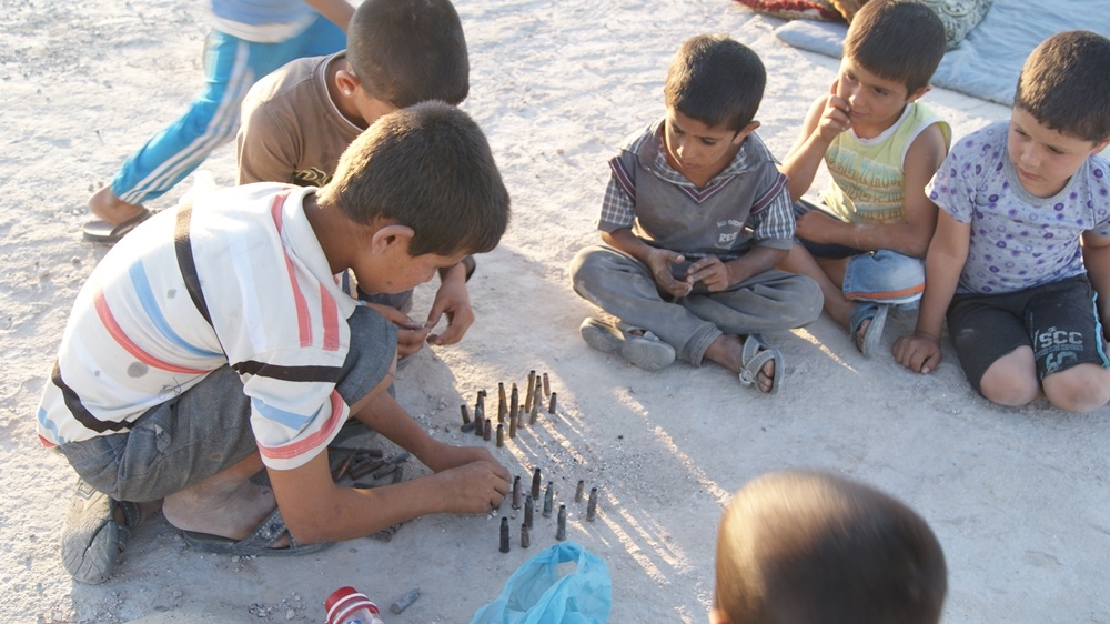 Kobane children play with bullet casings left behind after the five-month battle between ISIL and various Kurdish and Syrian rebel forces [Akhtin Asaad/Al Jazeera]