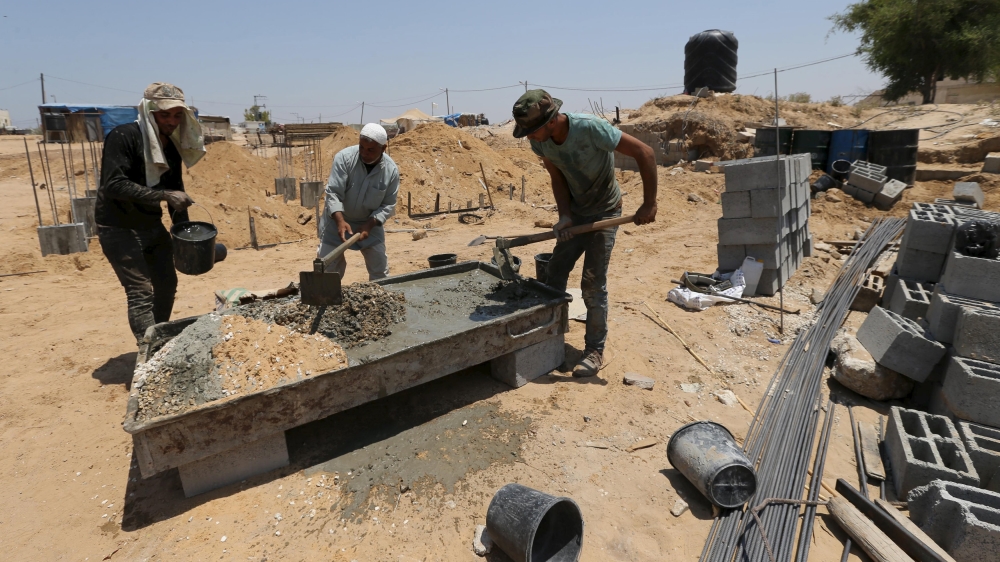 Palestinian labourers work at the construction site of a house, that witnesses said was destroyed by Israeli shelling during a 50-day war last summer
