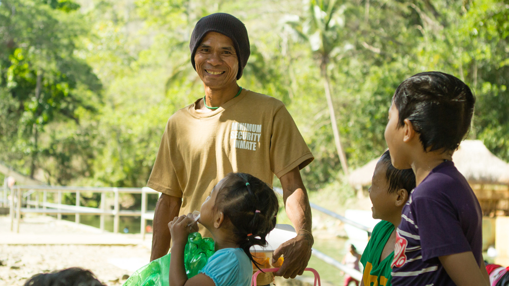 Minimum security inmate Edwin sells cookies and peanuts to children at Iwahig's natural swimming pool [Angel L Martinez Cantera/Al Jazeera]