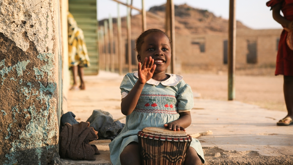 A young girl plays a drum in Jos, Nigeria [Fwangshak Joseph/Al Jazeera]
