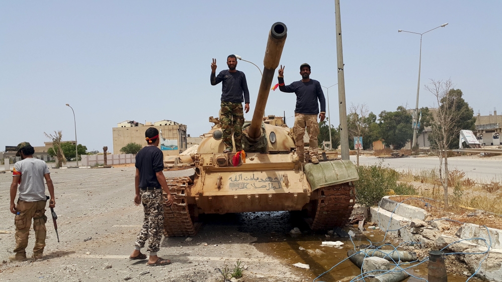 Members of the Libyan pro-government forces gesture as they stand on a tank in Benghazi