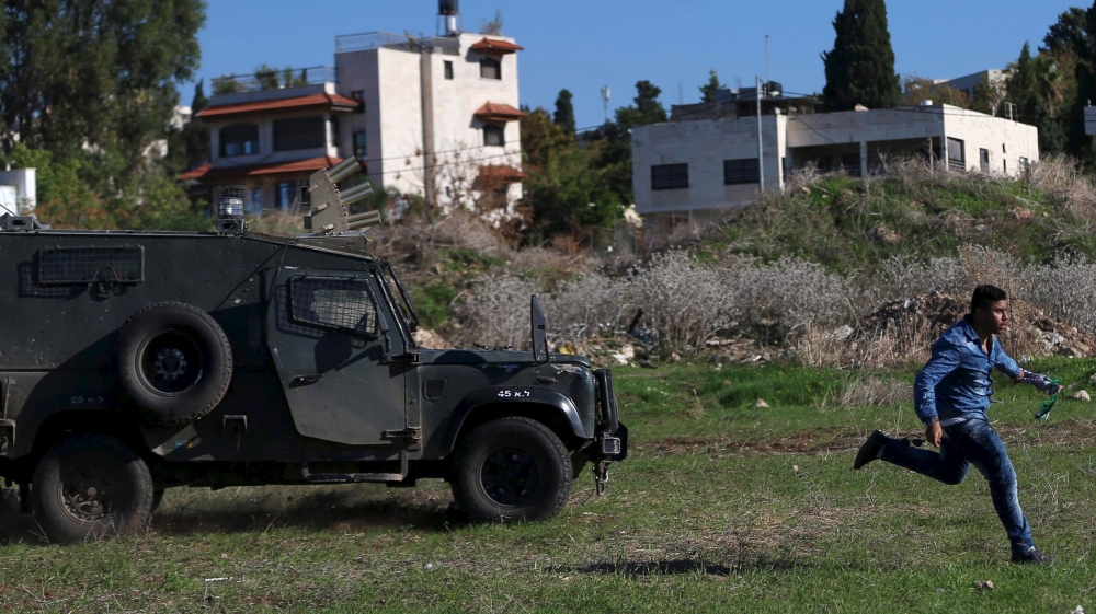 Palestinian runs in front of an Israeli border police jeep before he was detained during clashes in the West Bank city of Tulkarm