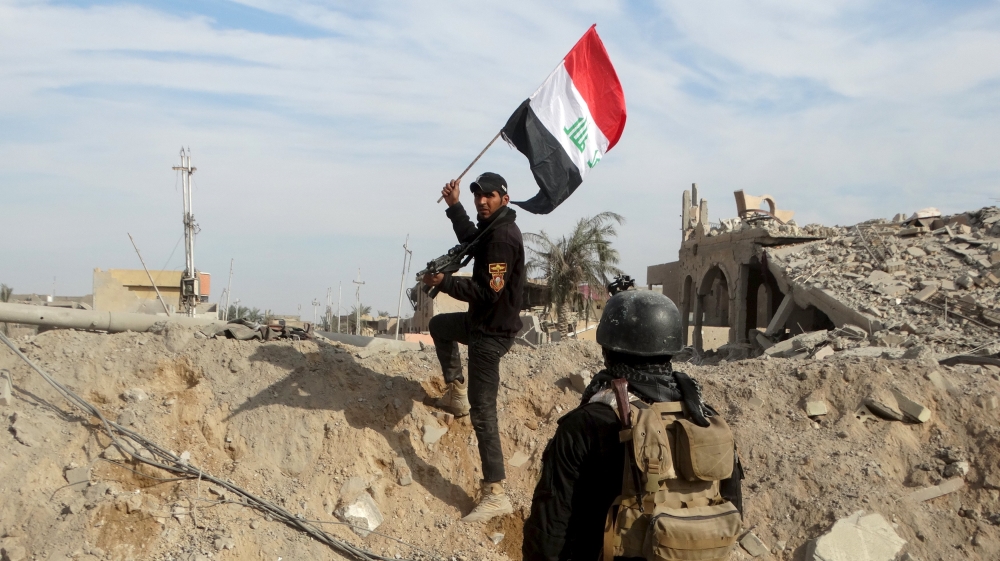 A member from the Iraqi security forces holds an Iraqi flag in the city of Ramadi