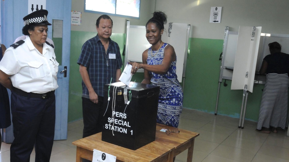 A police officer and an election official watch as a voter cast her ballot in the presidential polls in Victoria, Seychelles