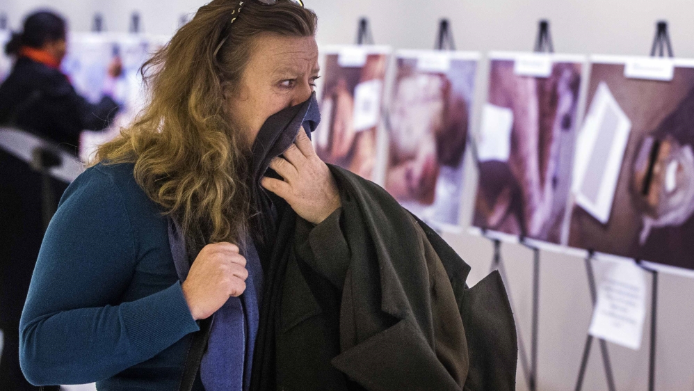 A woman reacts as she looks at a gruesome collection of images of dead bodies taken by a photographer, who has been identified by the code name "Caesar," at the United Nations Headquarters in New Yor