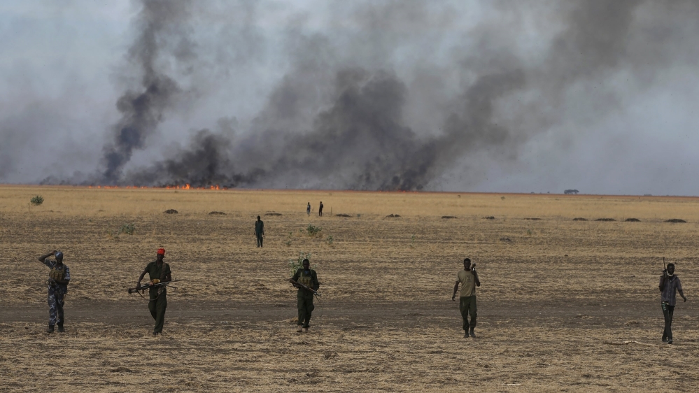 Rebel fighters walk in front of a bushfire in a rebel-controlled territory in Upper Nile State