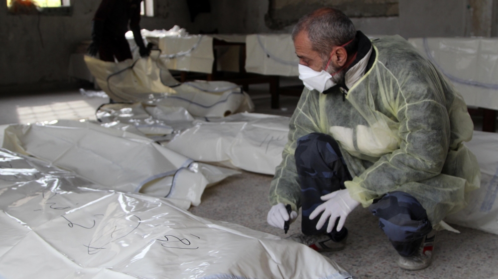 A coroner writes on a body bag at a morgue in Aleppo