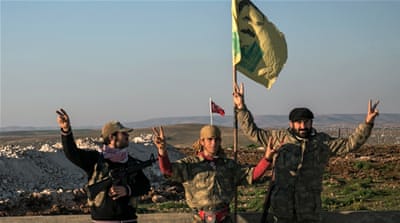 Syrian Kurdish militia members of YPG pose next to a poster of Abdullah Ocalan and a Turkish army tank in the background in Esme village in Aleppo province, Syria. [AP]