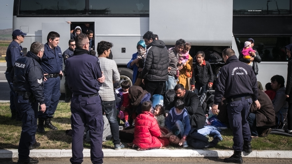 An Afghani woman faints after the police force some of her group to get on a bus to Athens [Nicola Zolin/Al Jazeera]  