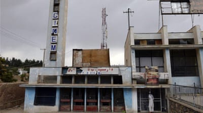 An Afghan man peers past the door to the abandoned Aryob Cinema in Kabul [AFP]
