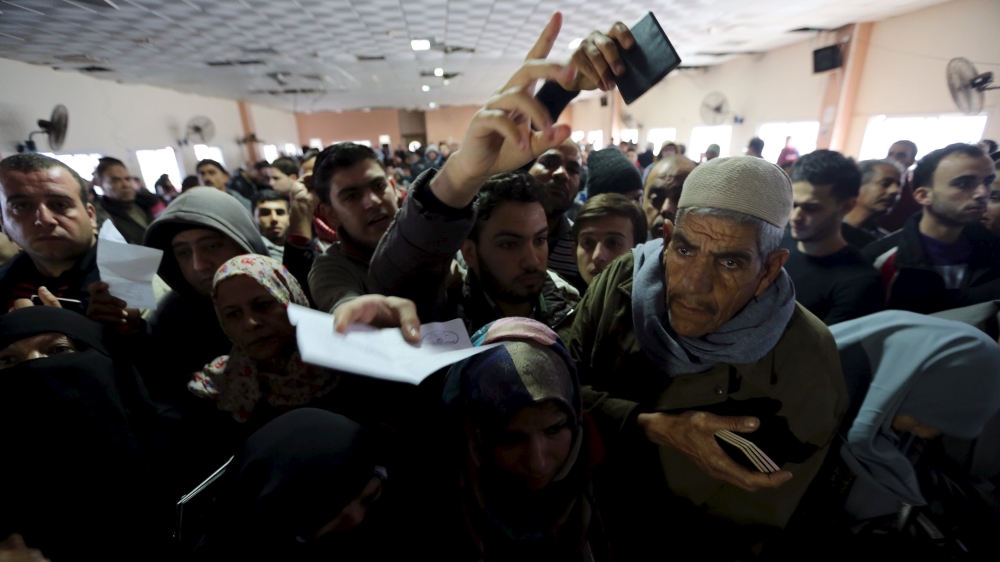 Palestinians present their documents as they wait for travel permits to cross into Egypt at the Rafah border crossing between Egypt and the southern Gaza Strip [REUTERS]