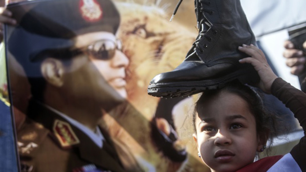 A supporter of Egypt''s President Abdel Fattah al-Sisi in the upcoming elections, holds a military boot on her head in a sign of support for military rule in 2014 [AFP]