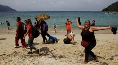 A Cuban migrant after crossing the border from Colombia through the jungle as tourists stand by in Panama [REUTERS]