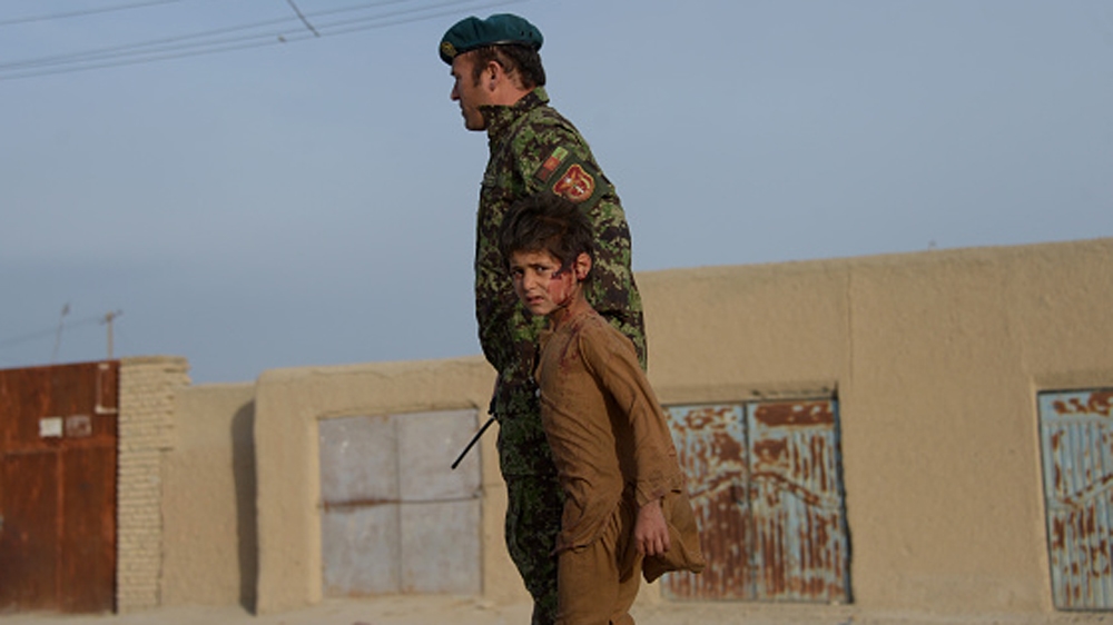 A wounded Afghan boy walks with an Afghan National Army (ANA) soldier at the site of a suicide attack in Dehdadi, a district close to the provincial capital Mazar-i-Sharif [Getty]