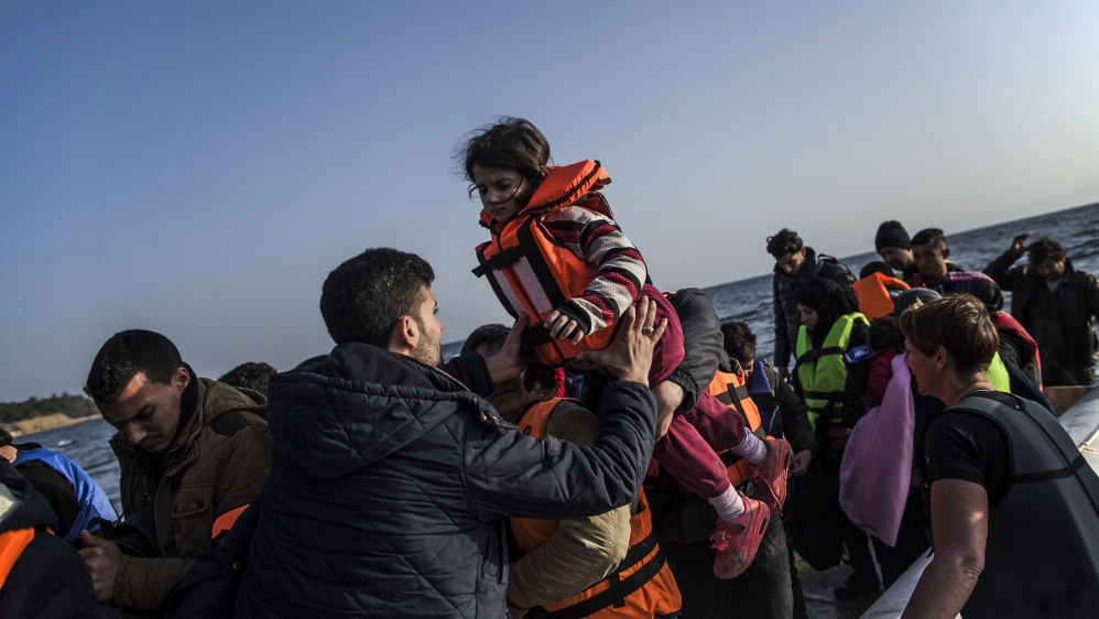 A Syrian man helps a girl to disembark from a dinghy after the arrival of refugees from the Turkish coast to the Greek island of Lesbos. [AP]