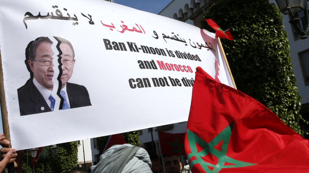 Protesters hold a banner and the Moroccan flag as they chant slogans during a rally