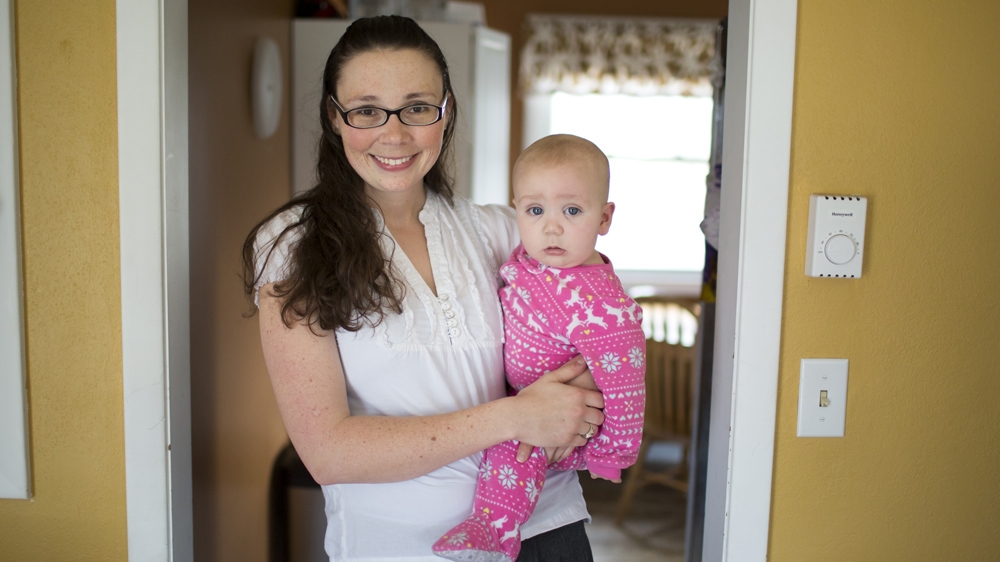 Lindsay Pappas poses for a portrait with her eight-month-old son, Gus. Pappas and her husband are both graduate students at Indiana University and have four children [James Brosher/Al Jazeera]   