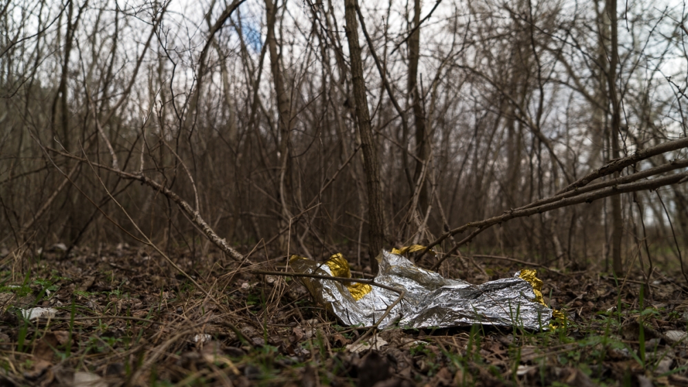 Sleeping bags, blankets and embers of campfires are all refugees leave behind as they move forward on their journey  [Sorin Furcoi/Al Jazeera]