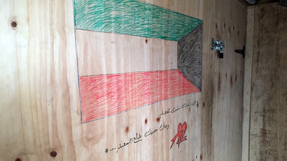 A Kuwaiti flag and verses from the national anthem at the entrance of one shack  [Shafik Mandhai/Al Jazeera]