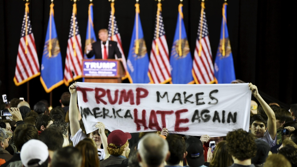 Protestors hold up a sign towards the crowd at a rally for Donald Trump at Oral Roberts University in Tulsa, Oklahoma on January 20 [Reuters]