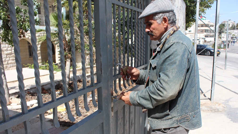 School principal Nabil Samara locks the front gate at the Beitunya boys' high school as the strike continues. [Mary Pelletier/Al Jazeera]
