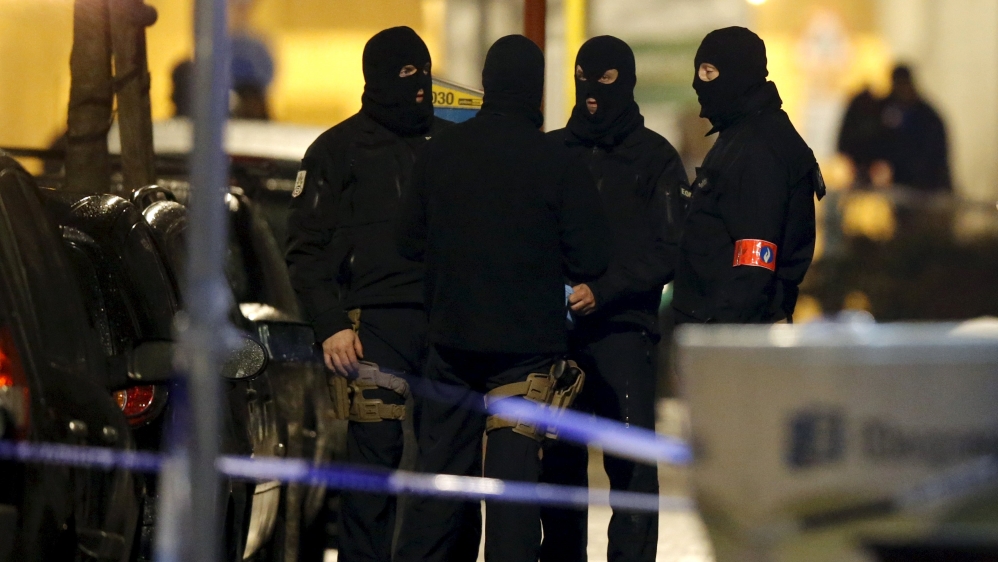 Masked Belgian police secure the entrance to a building in Schaerbeek during police operations in Brussels